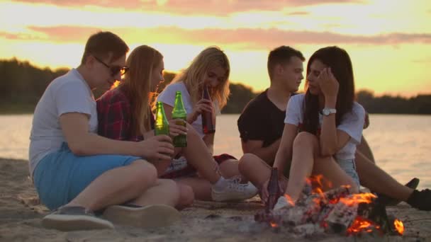 Młodzi ludzie cieszą się ciepłym letnim wieczorem na plaży — Wideo stockowe
