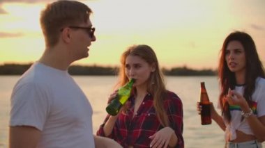 Öğrenciler plaj partisinde bira içiyor.