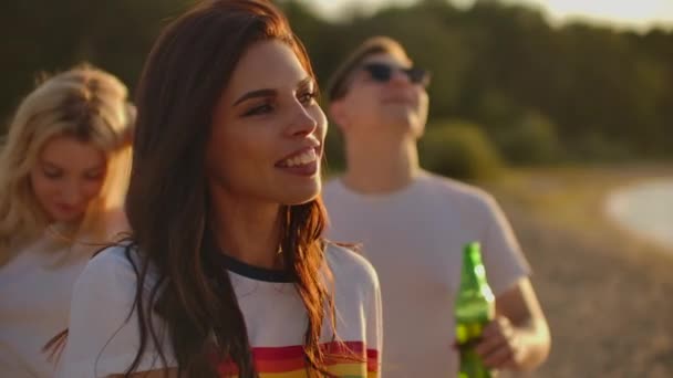 Студентка на вечеринке под открытым небом с пивом и друзьями — стоковое видео