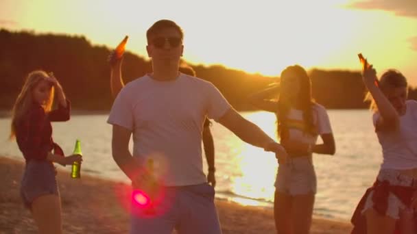 Den unge mannen dansar vid solnedgången på stranden. — Stockvideo