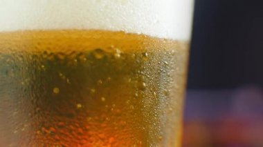 Biraya yakın çekim. Yarım litre soğuk bira, siyah arka planda izole edilmiş, rotasyon 360 derece. Su damlalı bir bardak bira.