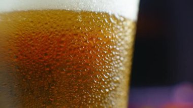 Biraya yakın çekim. Yarım litre soğuk bira, siyah arka planda izole edilmiş, rotasyon 360 derece. Su damlalı bir bardak bira.