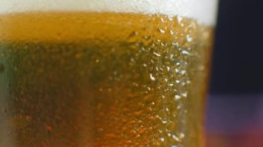 Biraya yakın çekim. Yarım litre soğuk bira, siyah arka planda izole edilmiş, rotasyon 360 derece. Su damlalı bir bardak bira.