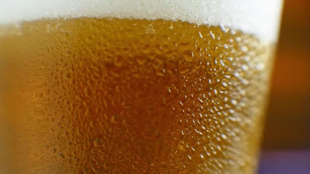 Macro shot of a beer glass with cold beer, bubbles rise in the glass. Slow motion beer bubbles. — Stock Video