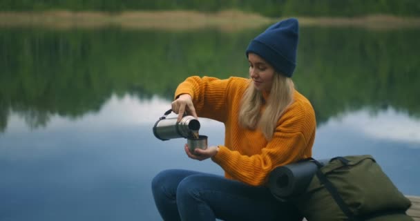 Piękne kobiety podróżnik lub Backpacker odpoczynku na niesamowity widok natury korzystających herbaty lub napojów z termosu unikalny zielony górskie jezioro w wakacje — Wideo stockowe