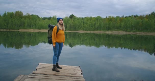 Кавказка путешественница на берегу знаменитого туристического озера в лесу. Концепция путешествия и приключений в лесу осенью и летом. Женщина смотрит на кресты лесного озера — стоковое видео