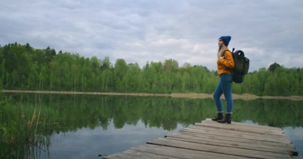 Кавказька жінка подорожувала на березі відомого туристичного озера в лісі. Концепція подорожей і пригод в лісі восени і влітку. Жінка дивиться на хрести лісового озера — стокове відео