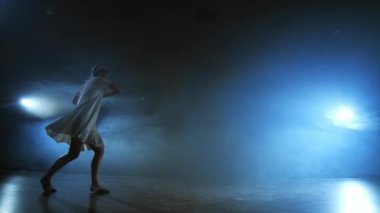 Ağır çekim: Duman içinde kadın dansçı. Modern bale sahnesinde yalınayak