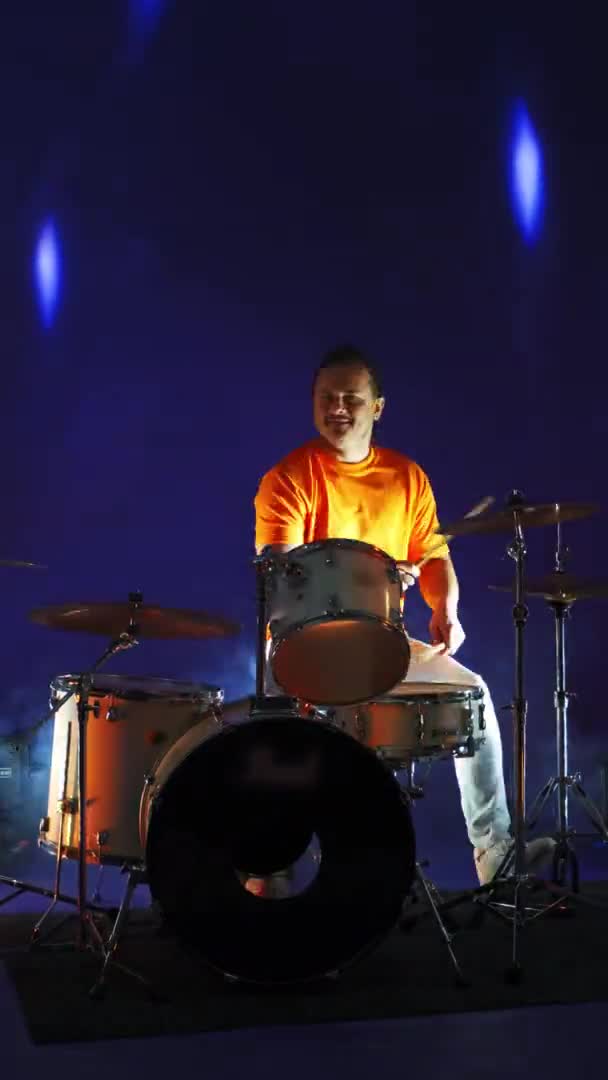 Człowiek grający na perkusji na ponurej scenie. Neonowe oświetlenie. Pionowe wideo. — Wideo stockowe