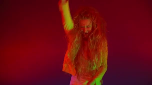 Funny unusual woman with long hair having fun, smiling, dancing in studio against blue background. Music, dance concept — Stock Video