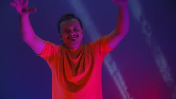 Szaleniec tańczący w neonowym świetle śmiesznego tańca. Zabawny człowiek na kolorowym niebieskim tle — Wideo stockowe