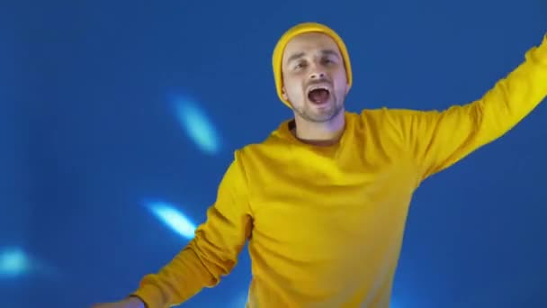 Smiling man dancing in studio. Joyful guy gesturing with hands. Man having fun. man smiling and dancing challenge dance in good mood on blue background.Unstoppable fun, happiness, comical portrait. — Stock Video