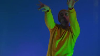 Mavi arka planda elleri izole bir şekilde dans eden adam. Parti, müzik, yaşam tarzı, radyo ve disko konsepti