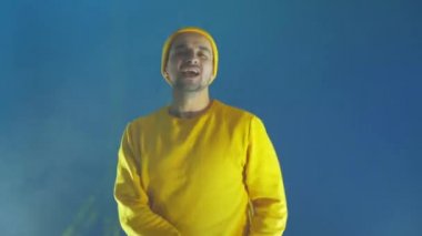 Adam neşeyle dans eder ve flaş ışıklarının ve renkli spot ışıklarının ışığında kameraya bakar. Neon renkleri ve çılgın adam müzik eşliğinde dans ediyor ve sarı bir ceket ve şapkayla şarkı söylüyor.