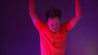 Çılgın adam dansın neon ışığında dans ediyor. Renkli mavi arka plandaki komik adam.