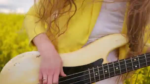 Närbild av en kvinna som spelar en gitarr hoppar och dansar kraftigt flytta hennes huvud och hår. Livekameran rör sig tillsammans med gitarristen i gul kostym. Rolig eldsjäl — Stockvideo