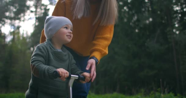 Pojken lär sig cykla i slow motion. Mamma hjälper pojken i träning. Begreppet stöd och stöd till barn. — Stockvideo