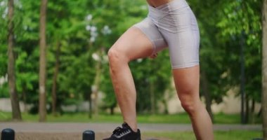 Parktaki genç bir kadın yazın spor giyim reyonunda atlama hareketleri yapıyor. Atletizm Kafkasyalı kadın parkta antrenman yapıyor..