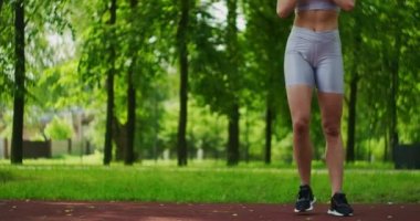 Dişi sporcu yan hamleler yapıyor. Parkta bacaklarını yavaş çekimde çalıştırıyor. Parkta spor yapan güzel bir kadın..