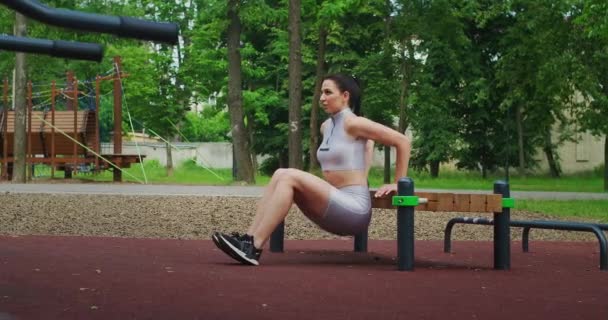 Fit vrouw doen omgekeerde push-ups met behulp van bank in een Park in slow motion. Mooie vrouw die sport in het park. — Stockvideo