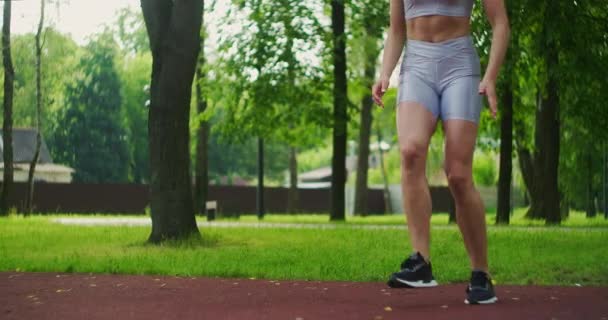 La atleta realiza embestidas laterales, resuelve sus piernas y salta en el parque en cámara lenta. Hermosa mujer practicando deportes en el Parque . — Vídeo de stock