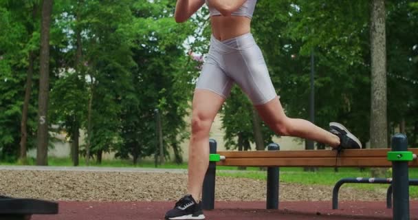 Athletics trains in the Park on a bench performing lunges squats on one youth — Stock Video