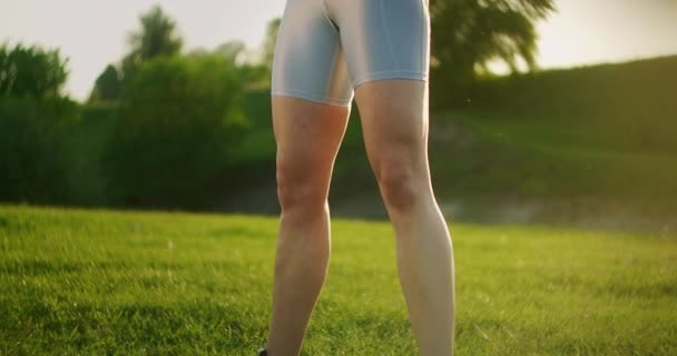 Sportowa kobieta w parku przykuca z hantlami w rękach o zachodzie słońca. Trening wagi na świeżym powietrzu. Fitness w parku publicznym w lecie dla ud i nóg. — Wideo stockowe