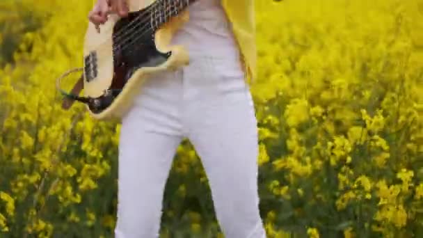 Una donna suona una chitarra rock o metal salta e balla scuotendo la testa e i capelli. La telecamera in diretta si muove con il chitarrista in abito giallo. — Video Stock