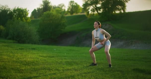 Cardio es un entrenamiento circular de mujeres en el parque. Las mujeres jóvenes entrenan y hacen ejercicio con saltos — Vídeos de Stock