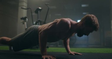 Güçlü bir adam, tüm gücüyle yerden şınav çeker. Pompalı bir adam spor salonunda şınav çeker.