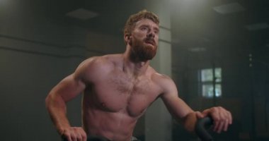 Formda bir adam spor salonunda sabit bir bisikletle yorgunluk trenlerinin üstesinden geliyor. Atmosferik spor salonu. rahatlama sporcusu