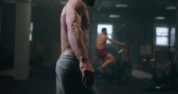 Egy férfi testépítő hajlítja a karját, és készül egy edzés a tornateremben. — Stock videók