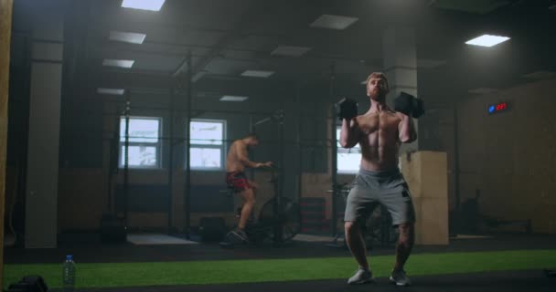 Egy atlétikai férfi póló nélkül súlyzózik a tornateremben. súlyemelés az edzés alatt. — Stock videók