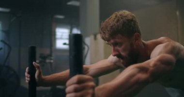 Azimli bir erkek sporcu spor salonunda ağır bir kızağı itiyor. Dayanıklılık için ağır bir ağırlık ile egzersiz