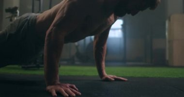 Güçlü bir adam, tüm gücüyle yerden şınav çeker. Pompalı bir adam spor salonunda şınav çeker.