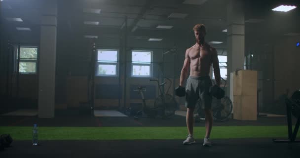 Mężczyzna bez koszuli pociągi podnosząc hantle w siłowni — Wideo stockowe