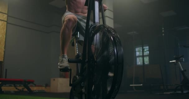 남자가 느린 동작으로 체육관에서 에어로빅을 타는 것을 지배 한다. 움직이지 않는 자전거에서 심장 훈련을 하는 모습 — 비디오