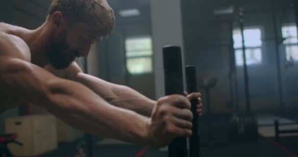 Svalnatý muž tlačí sáně v tělocvičně během cvičení zpomalit — Stock video