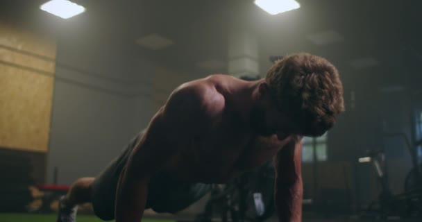 Ένας δυνατός άντρας εκτελεί push-UPS από το πάτωμα με όλη του τη δύναμη. Ένας φουσκωτός άντρας κάνει push-UPS στο γυμναστήριο. — Αρχείο Βίντεο