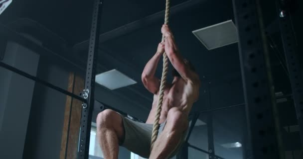 Ein Mann mit nacktem Oberkörper klettert während eines Trainings in der Turnhalle in Zeitlupe auf ein Seil — Stockvideo