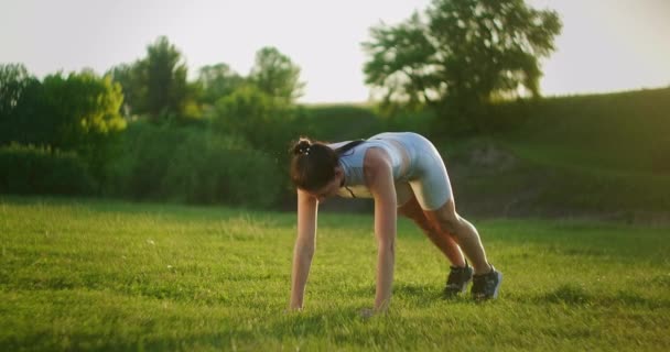 Atleta donna coinvolta nel fitness nel parco, facendo sollevamenti delle gambe sul tappeto. Allenati. Lavorare su un bel corpo al mattino o al tramonto. Esercizi per i muscoli delle gambe e dell'anca — Video Stock