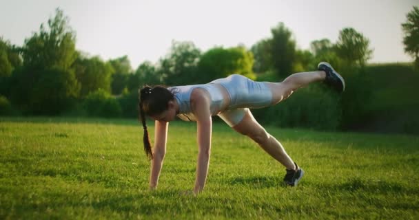 Atleta donna coinvolta nel fitness nel parco, facendo sollevamenti delle gambe sul tappeto. Allenati. Lavorare su un bel corpo al mattino o al tramonto. Esercizi per i muscoli delle gambe e dell'anca — Video Stock
