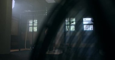 Genç atletik beyaz adam soyunma odasında ağırlık kaldırırken yavaş çekimde egzersiz yapıyor. Kollarını halterlere bağlayıp kemerlerini bağlayın.. 