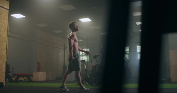 Ya está buscando el próximo desafío. Atleta muscular cansado. Hombre cansado descansando después del entrenamiento. Atleta masculino cansado y agotado sentado en el suelo en el gimnasio con una botella de agua . — Vídeos de Stock