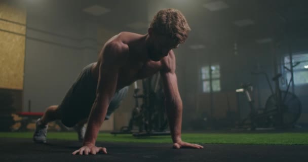 Hombre haciendo flexiones en un gimnasio. Exhalar e inhalar después de flexiones y ejercicio. Perfecto para fitness y entrenamiento. Joven deportista realiza flexiones en el gimnasio. El atleta se dedica a fitnes — Vídeos de Stock