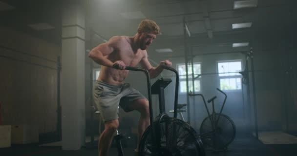 Fitness-Mann auf dem Fahrrad beim Spinning im Fitnessstudio. Fit junge Männer, die auf dem Fitnessrad trainieren. Männliche Gymnastik auf dem Fahrrad im Fitnessstudio — Stockvideo