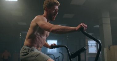Genç adam spor salonunda egzersiz bisikleti kullanıyor. Fitness erkeği spor salonunda hava bisikleti kullanıyor. Ekipman, çaba.