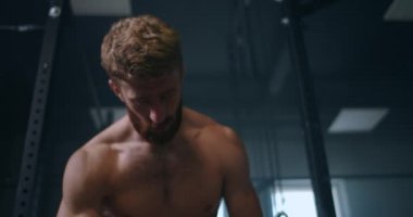 Şimdiden bir sonraki müsabakayı bekliyor. Yorgun kas atleti. Yorgun adam antrenmandan sonra dinleniyor. Spor salonunda elinde su şişesiyle oturan yorgun ve bitkin bir erkek sporcu..