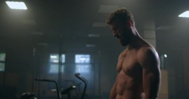 Dinlenme zamanı. Spor kıyafetli genç bir adam spor salonunda pencerenin önünde dururken bitkin görünüyor..