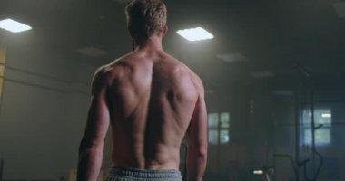 Dinlenme zamanı. Spor kıyafetli genç bir adam spor salonunda pencerenin önünde dururken bitkin görünüyor..